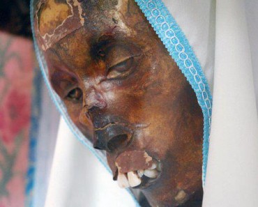 A mummified face is shrouded in a white nun's habit.