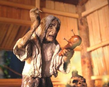 Sculpture of a haggard mangkukulam witch in her abode. She is placing large needles into a voodoo doll.