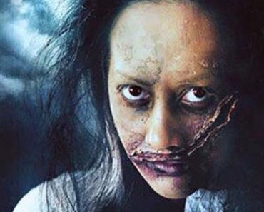 A filipina is shown with unkempt hair and dark circles under her eyes. A large slash wound crosses her face from the right of her mouth up to the left side of her eye.