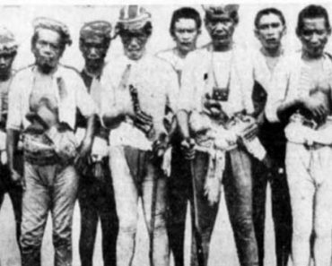 10 Juramentados stand in traditional Moro attire, armed with swords, guns, and knives.