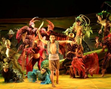 Tanghalang Pilipino's stage production of the Ibalong. Handyong stand at the front with bolo raised high above his head. All sorts of costumed beasts lurk behind him.