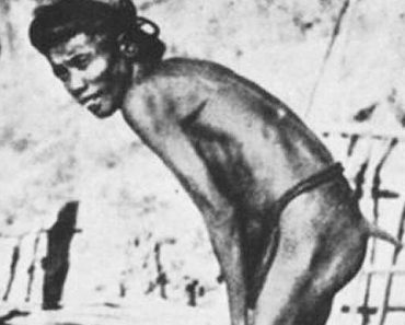 A side view of an Igorot man. He is slightly hunched over and only wearing a bahag (loin cloth). The way it is tied makes it appear that he has an eight inch tail coming from above his buttock.