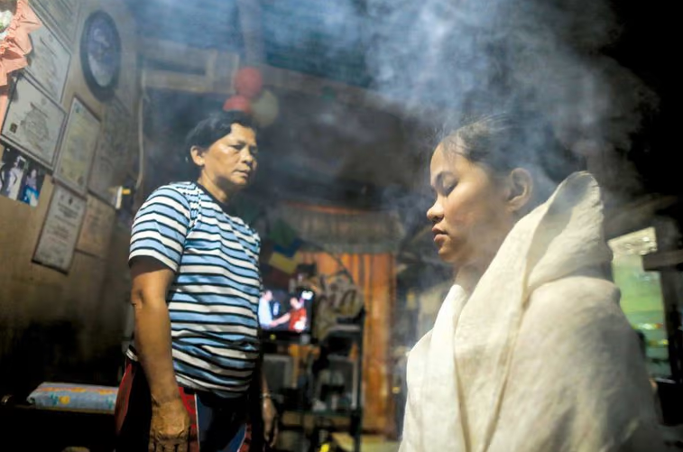 A mother sits in a robe surrounded by steam.